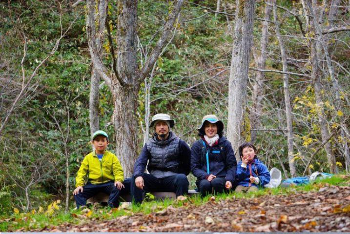 山道のベンチに腰掛けている岩崎さん家族4人の登山中の記念撮影の写真