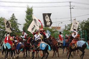 イベントにて、乗馬している団体を映した写真。八龍神の旗や「武」と書かれた旗も写っている。また、ジョッキーの衣装は戦国武将や貴族の恰好をしている。