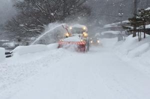 深く雪の積もった街道を除雪車が走る写真