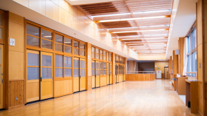 明るい色の木製の壁や扉、広いフローリングの廊下が広がる校舎内の写真