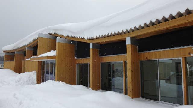 地域交流施設ホシッバの家で、屋根や周囲の地面に雪が降り積もっている様子の写真