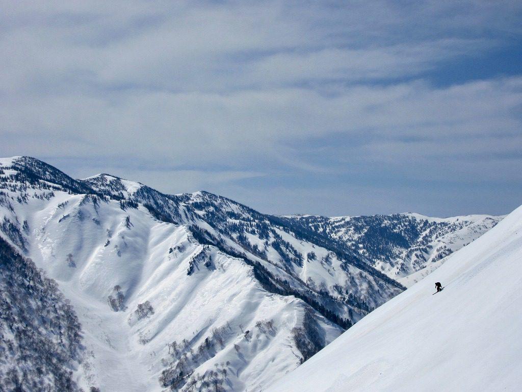 青空の下、雪化粧をした坪入山の写真、奥に三ツ岩岳が見えている