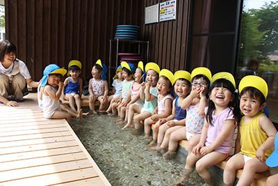 たくさんの子供たちが楽しそうに足湯に浸かっている光景の写真。